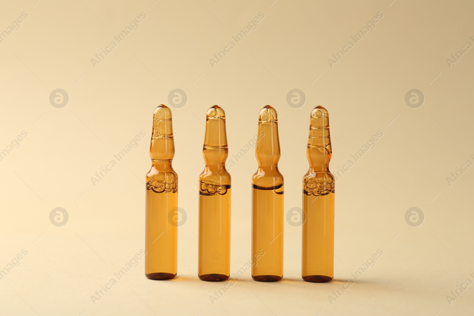 Photo of Glass ampoules with liquid on beige background