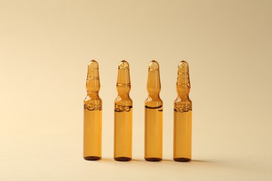 Photo of Glass ampoules with liquid on beige background