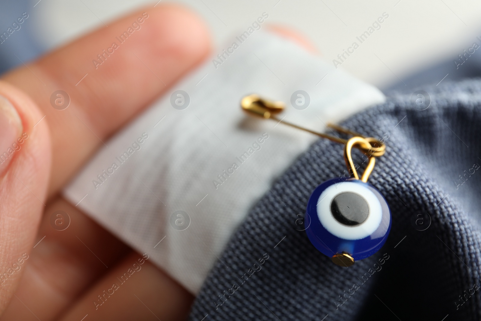 Photo of Woman holding clothing with evil eye safety pin, closeup