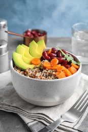 Photo of Healthy quinoa salad with vegetables in bowl served on table