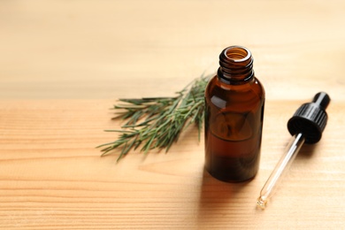 Photo of Bottle of natural tea tree oil, dropper and plant on table, space for text