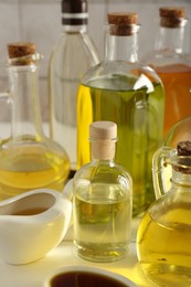 Photo of Vegetable fats. Different oils in glass bottles on white table, closeup