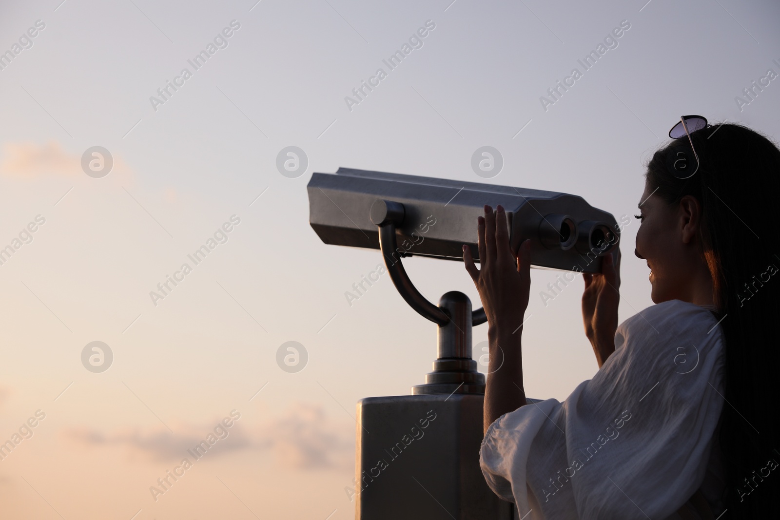 Photo of Young woman looking through tourist viewing machine at observation deck, space for text