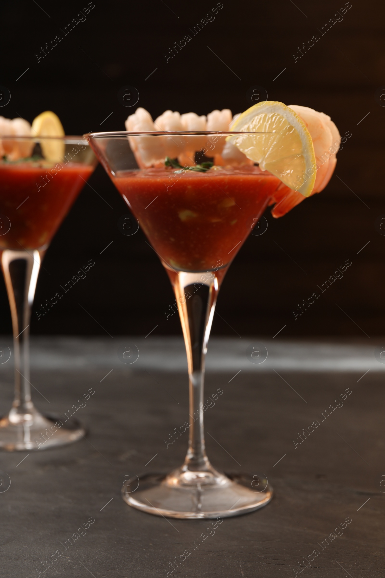 Photo of Tasty shrimp cocktail with sauce in glasses and lemon on grey table, closeup