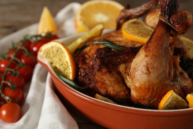Photo of Tasty baked chicken with orange slices on table, closeup