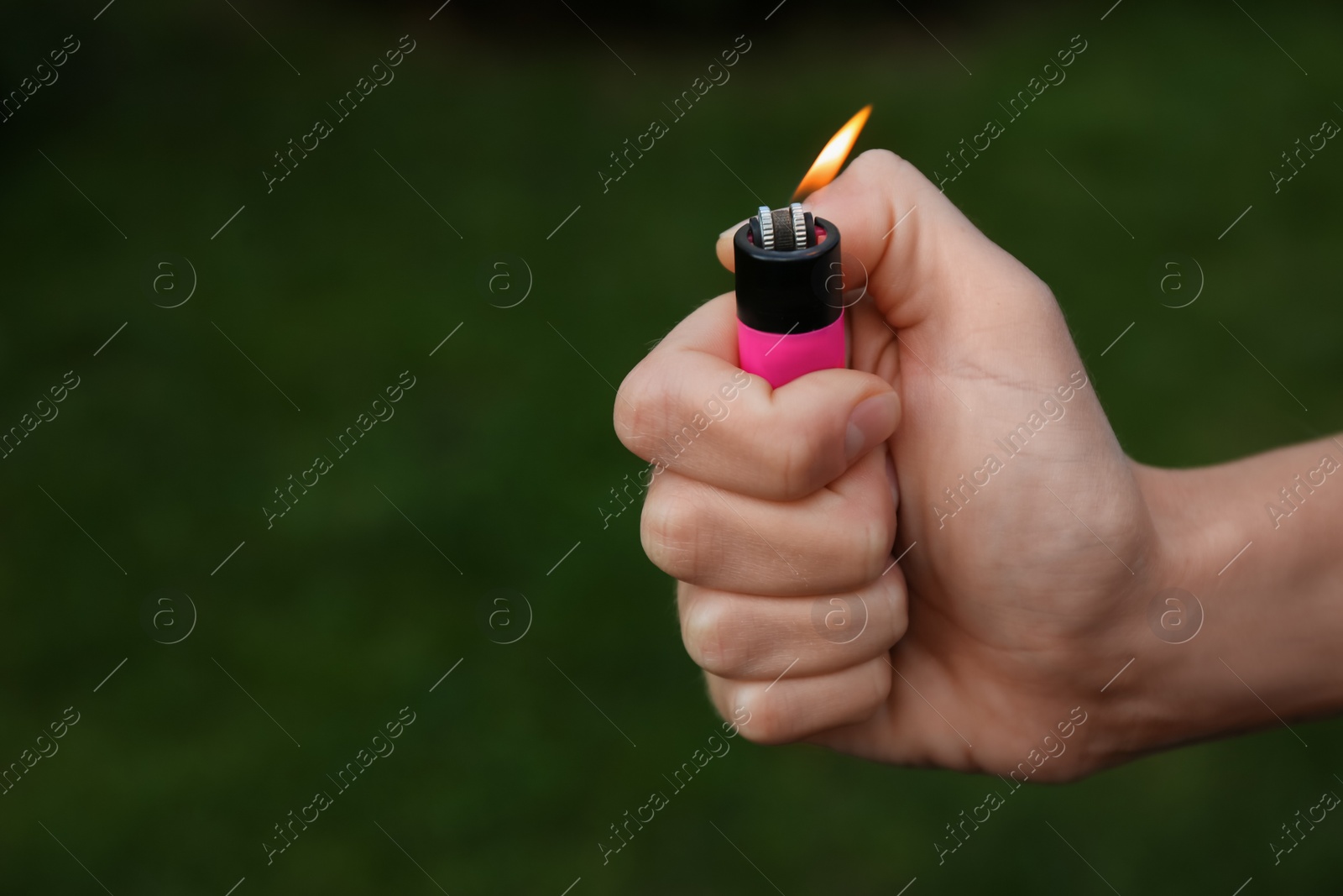 Photo of Man holding lighter with burning flame outdoors, closeup. Space for text