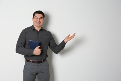 Photo of Portrait of male teacher with notebooks on light background