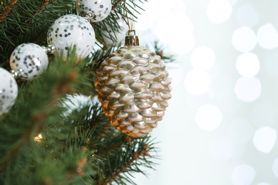 Photo of Cone shaped holiday bauble hanging on Christmas tree against blurred lights, closeup