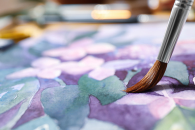 Photo of Painting flowers with watercolor on paper, closeup