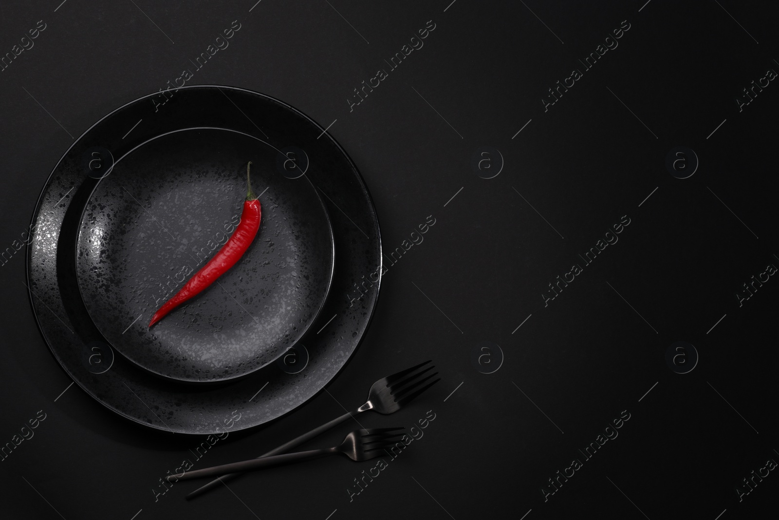 Photo of Stylish table setting. Plates, cutlery and red chilli pepper on black background, top view with space for text