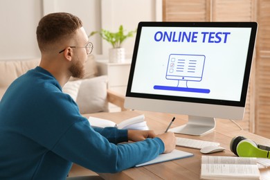 Photo of Man taking online test on computer at desk indoors