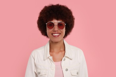 Portrait of young woman in sunglasses on pink background