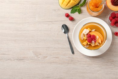 Photo of Delicious mango jelly with fresh raspberries and almond flakes on light wooden table, flat lay. Space for text