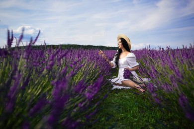 Beautiful young woman sitting in lavender field