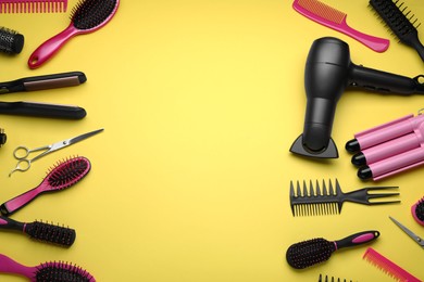 Flat lay composition of professional hairdresser tools on yellow background, space for text