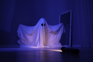 Creepy ghost. Woman covered with sheet in blue light