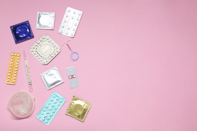 Contraceptive pills, condoms, intrauterine device and thermometer on pink background, flat lay and space for text. Different birth control methods