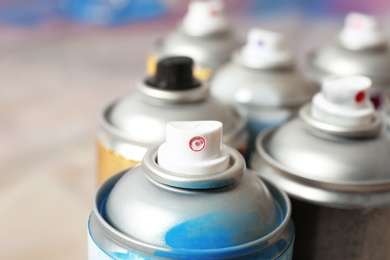 Photo of Used cans of spray paint on blurred background, closeup view