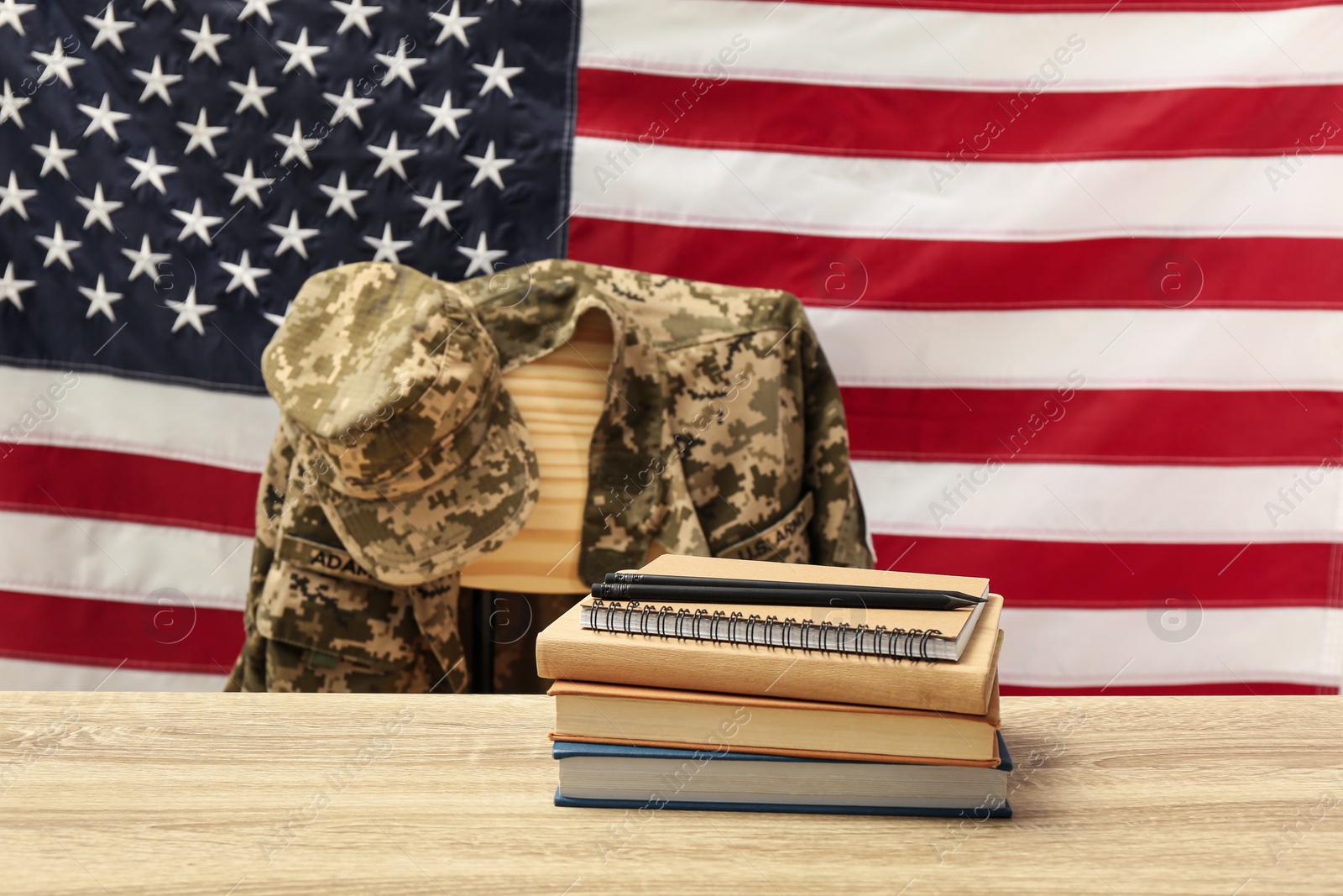 Photo of Notebooks and soldier uniform near flag of United States. Military education