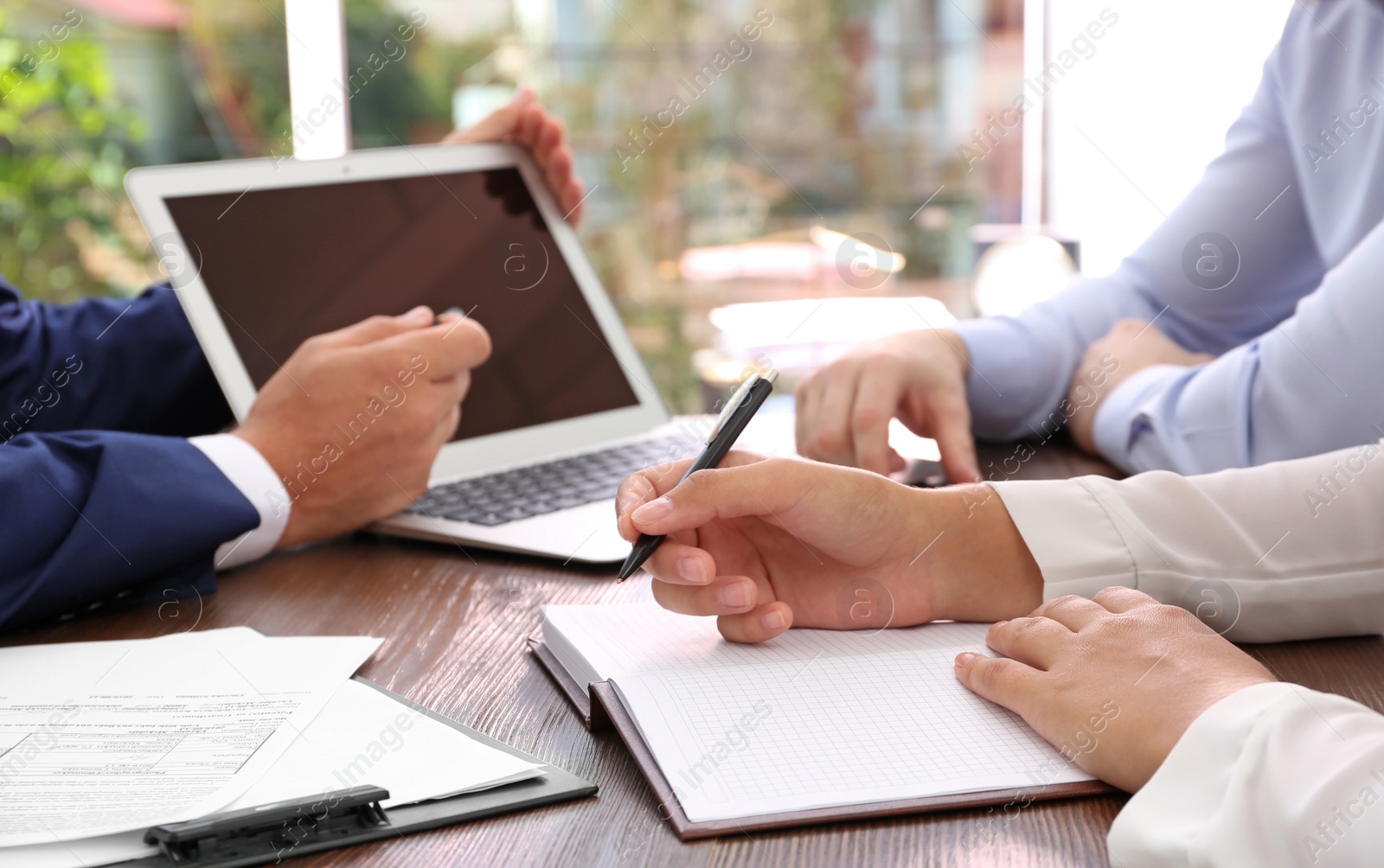 Photo of Lawyer working with clients at table in office, focus on hands