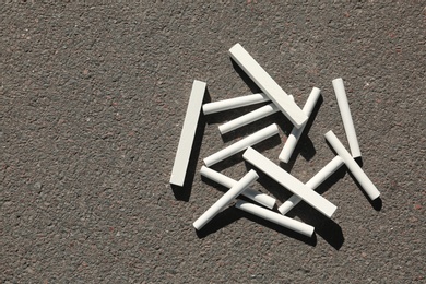 Photo of White chalk sticks on asphalt, top view