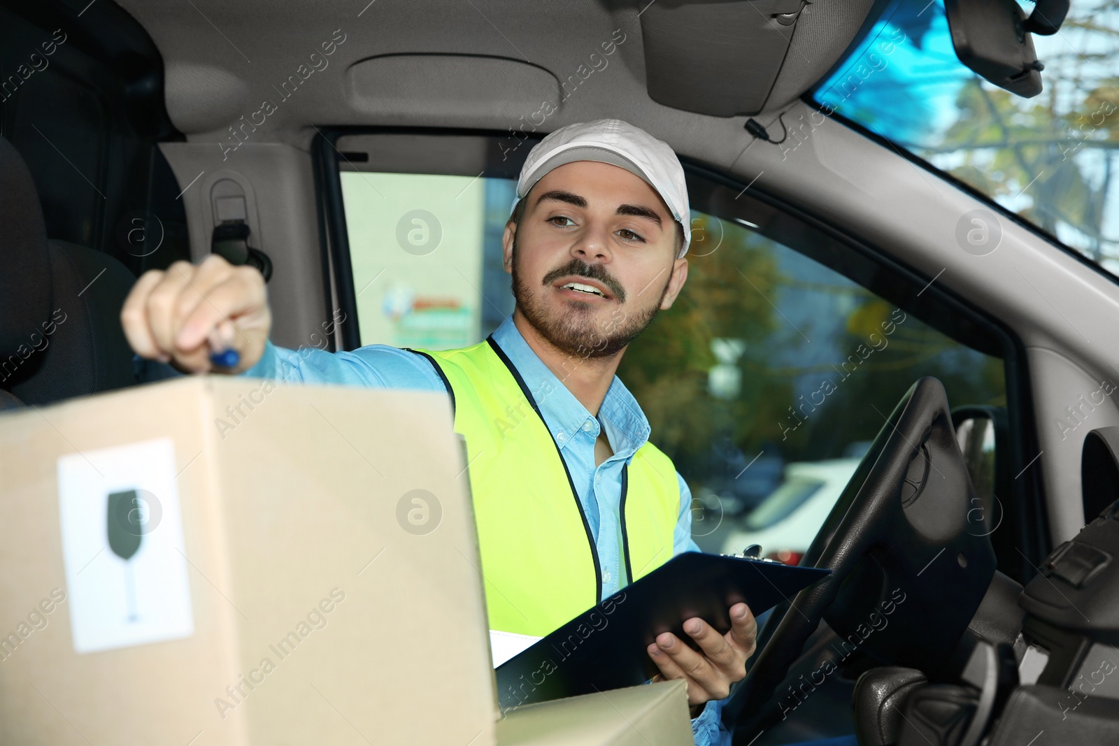 Photo of Young courier checking amount of parcels in delivery van