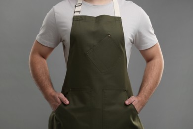 Man in kitchen apron on grey background, closeup. Mockup for design