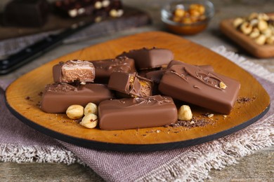 Photo of Delicious chocolate candy bars with nuts on wooden table, closeup