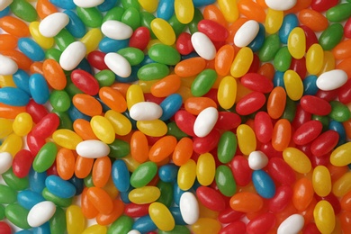 Tasty bright jelly beans as background, top view