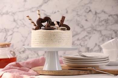 Delicious cake decorated with sweets and tableware on white table