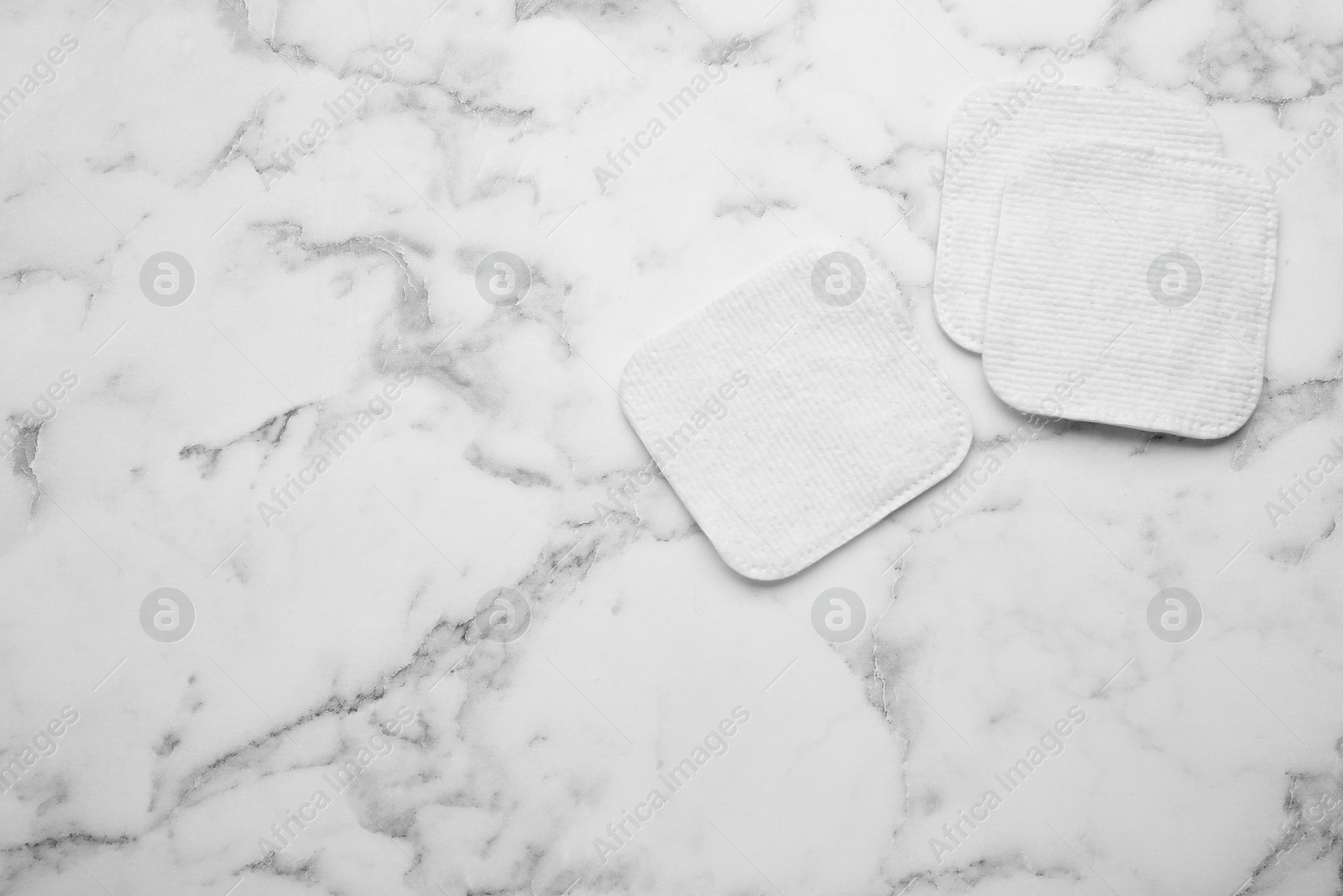 Photo of Clean cotton pads on white marble table, flat lay. Space for text