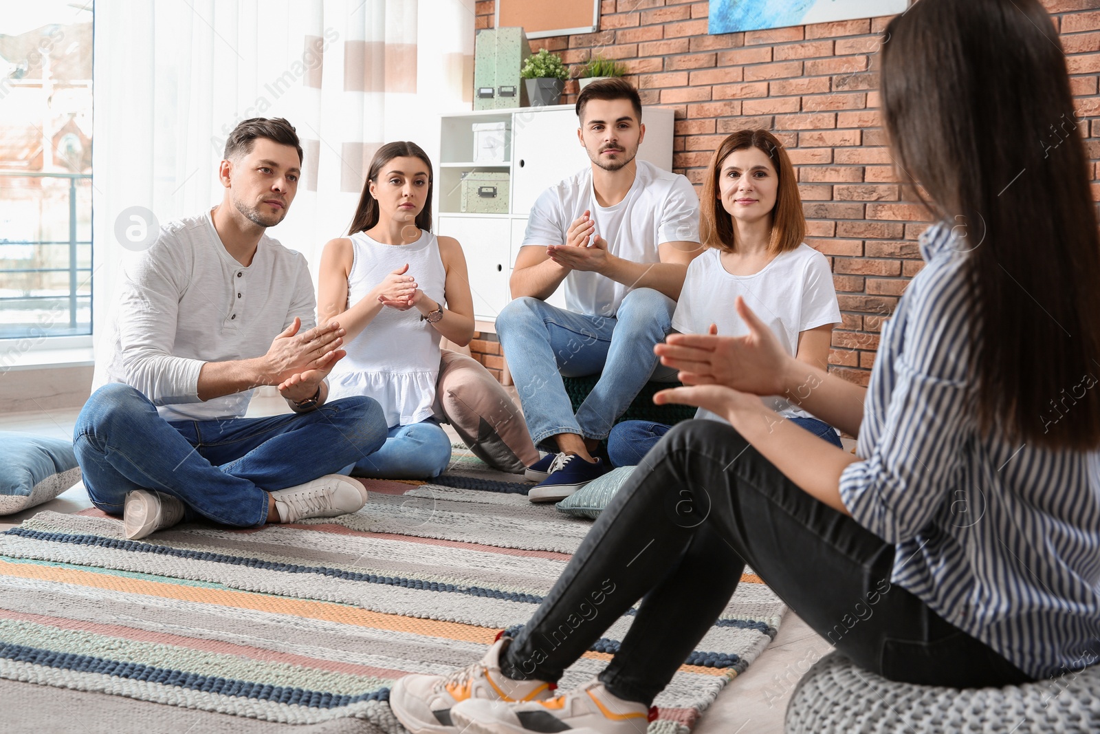 Photo of Group of young people learning sign language with teacher indoors