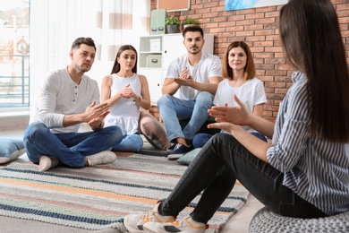 Photo of Group of young people learning sign language with teacher indoors