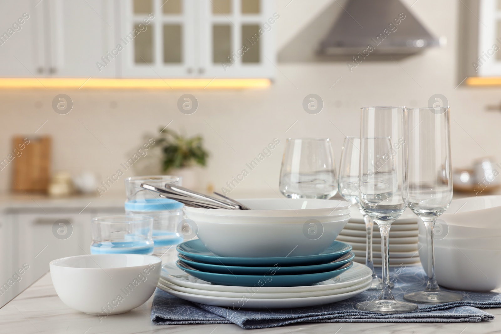 Photo of Different clean dishware, cutlery and glasses on white table in kitchen