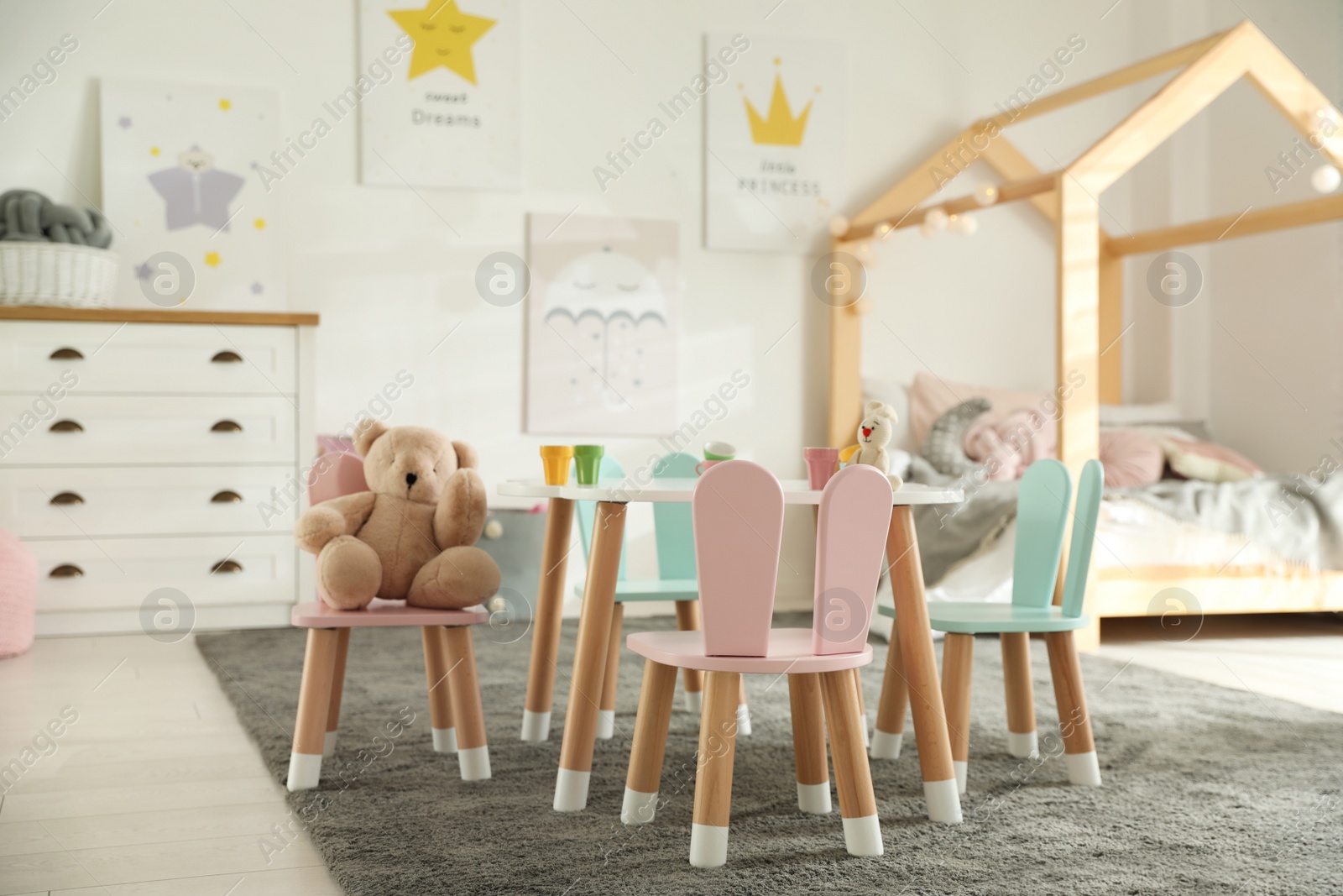 Photo of Small table and chairs with bunny ears in children's bedroom interior