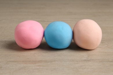 Different color play dough on wooden table, closeup