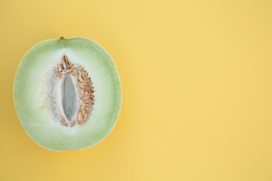 Half of fresh ripe honeydew melon on yellow background, top view. Space for text