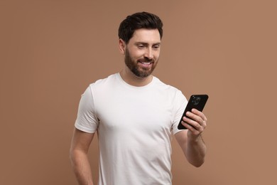 Photo of Smiling man with smartphone on light brown background