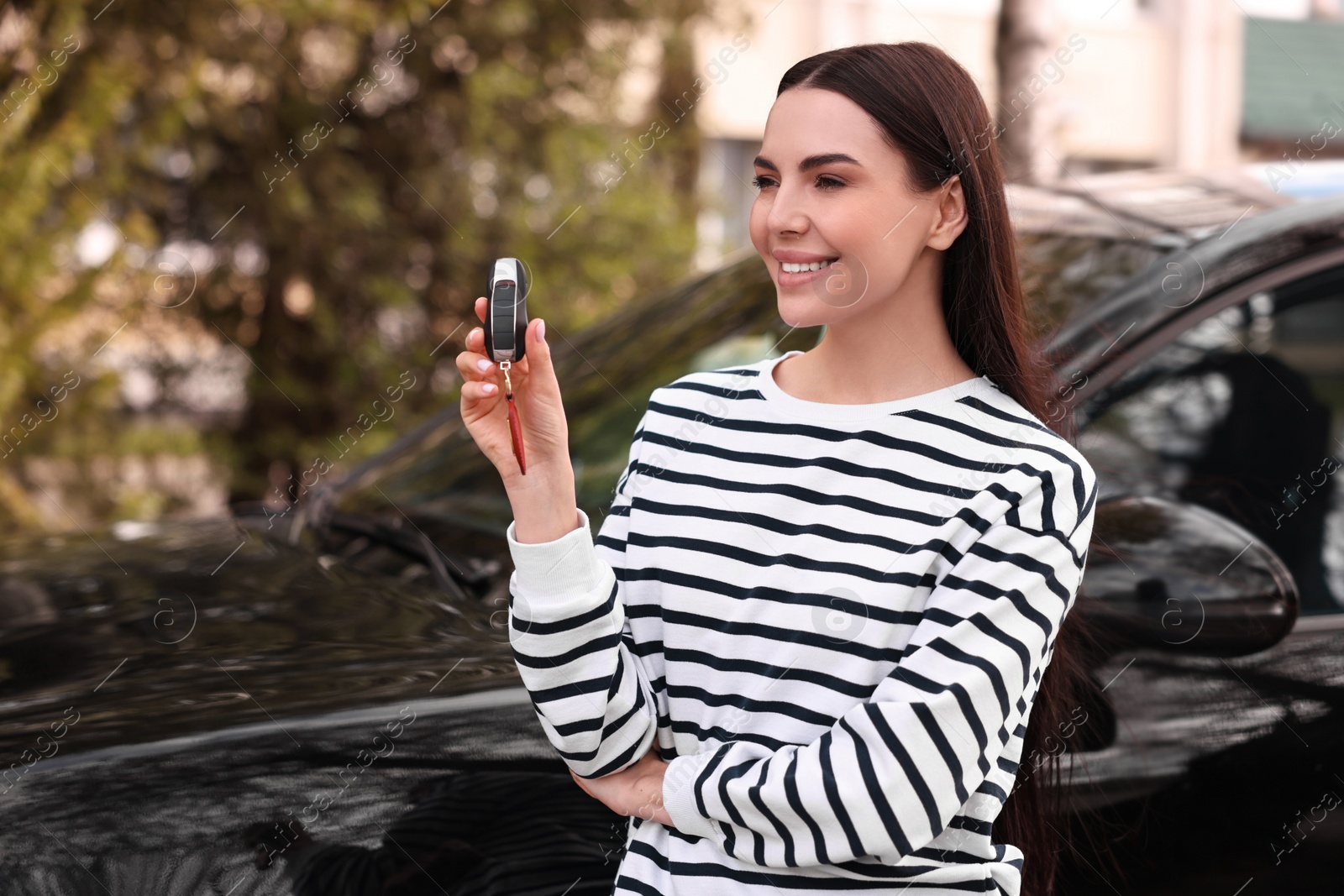 Photo of Woman holding car flip key near her vehicle outdoors