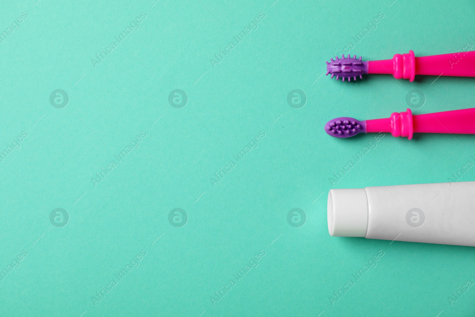 Photo of Baby toothbrushes and toothpaste with space for text on color background, top view