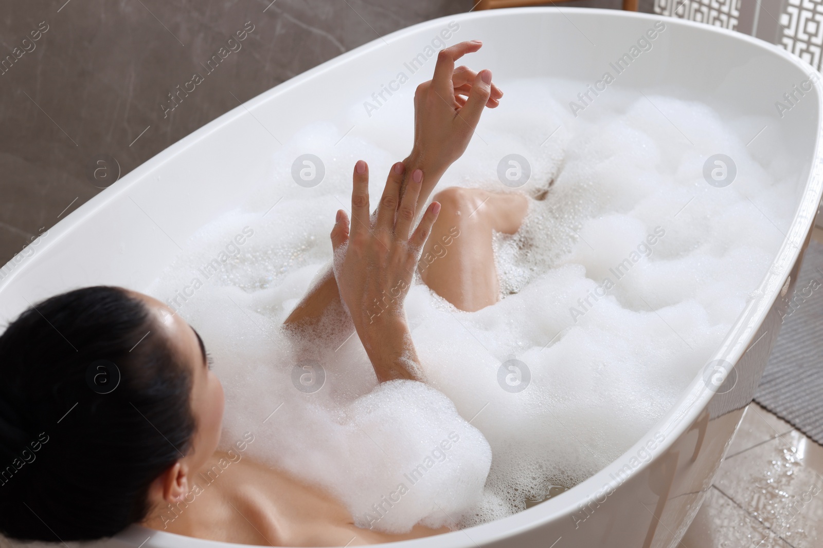 Photo of Woman taking bath with shower gel indoors