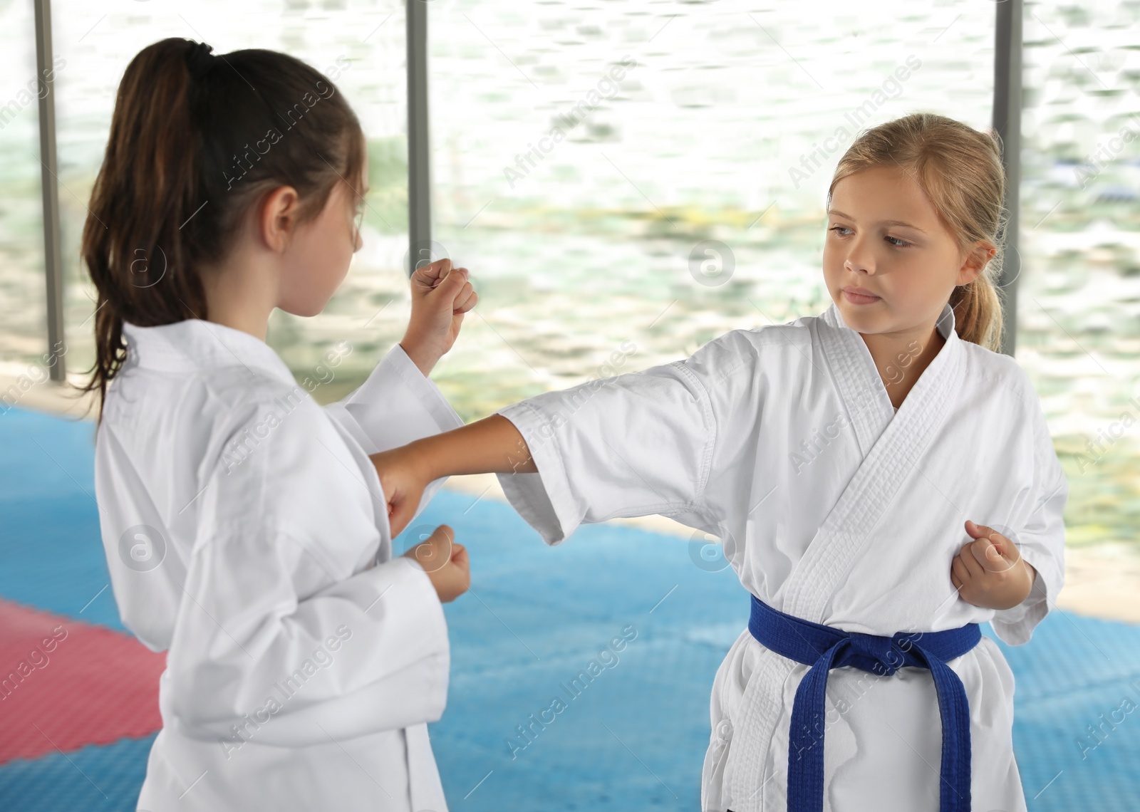 Photo of Children in kimono practicing karate on tatami outdoors