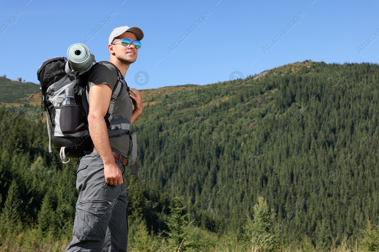 Photo of Man with backpack and sleeping mat in mountains. Space for text