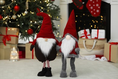 Photo of Funny Christmas gnomes on floor in decorated room