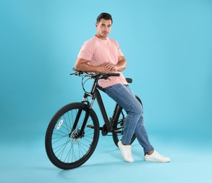 Photo of Handsome young man with modern bicycle on light blue background