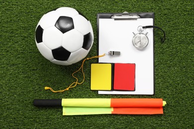 Photo of Soccer ball and different referee equipment on green grass, flat lay