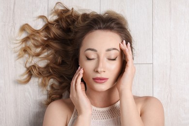 Portrait of beautiful woman with closed eyes on wooden floor, top view