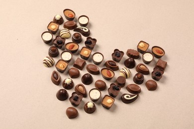 Photo of Heart made with delicious chocolate candies on beige background, above view