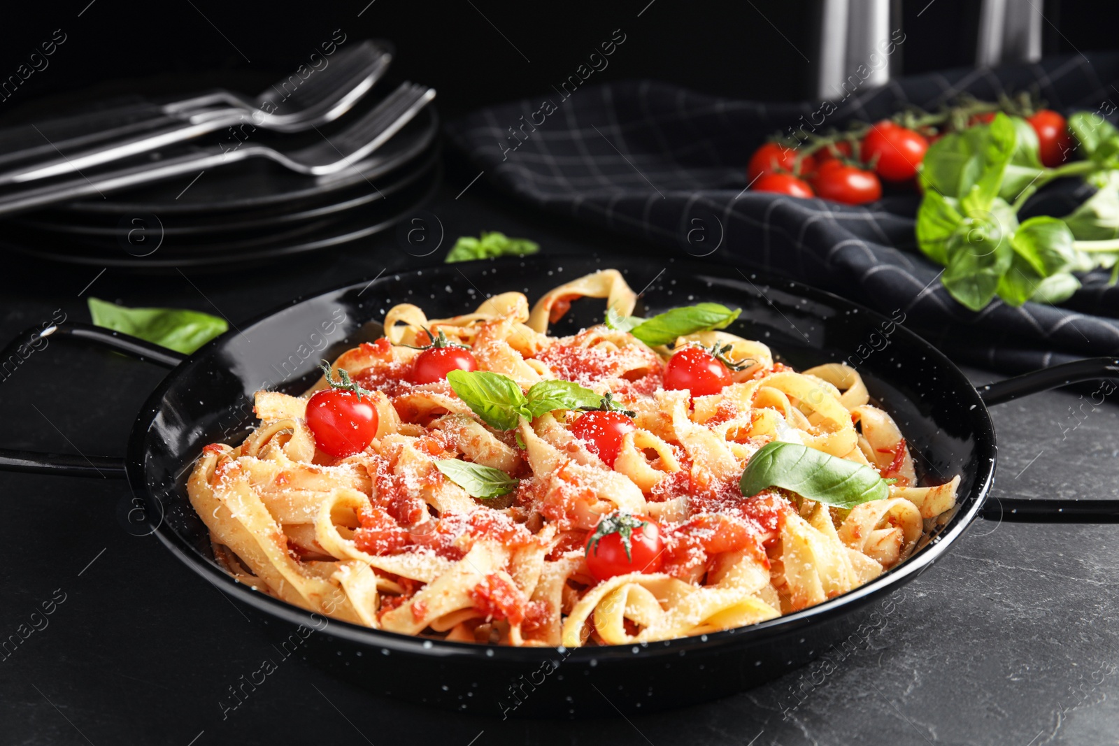 Photo of Tasty pasta with tomatoes, cheese and basil on black table