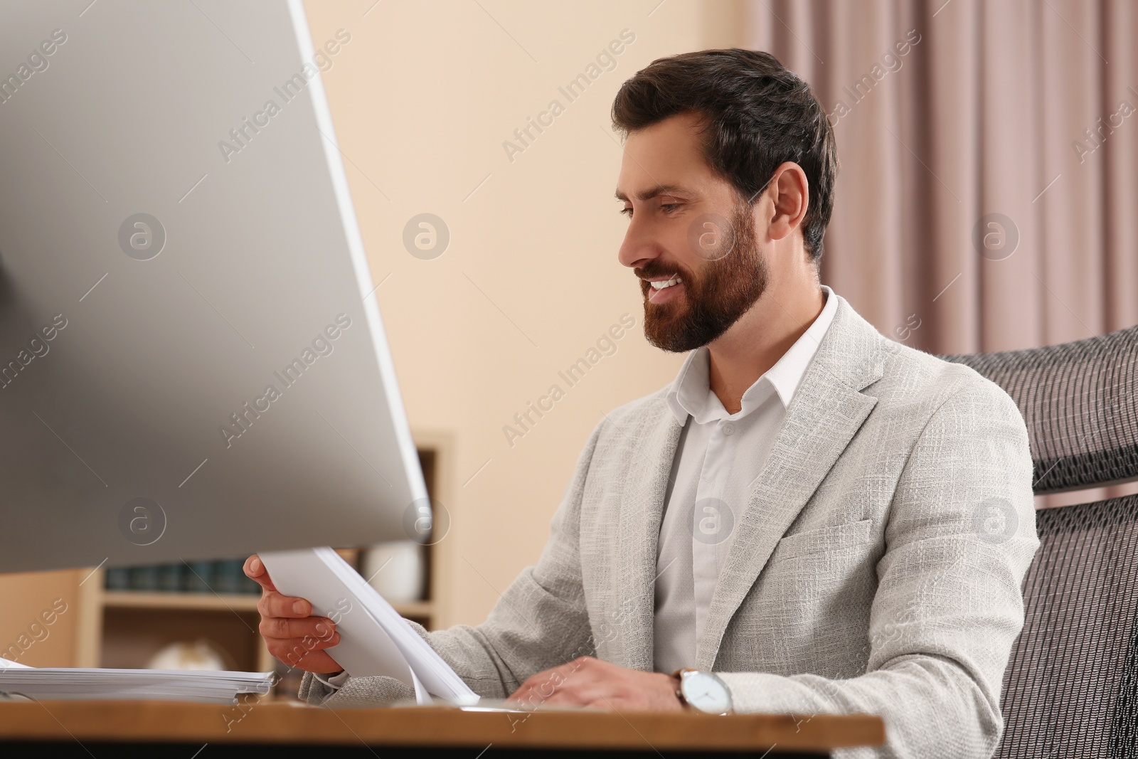 Photo of Happy businessman working with documents at table in office